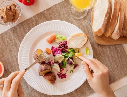 Top view of a nutritious breakfast setup with salad, bread, and fresh juice, perfect for a healthy start.