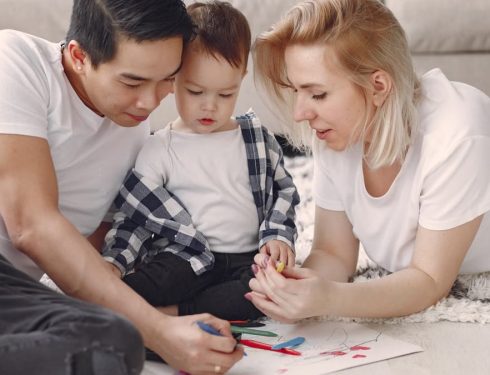 Loving family creating art together, fostering play and connection indoors.
